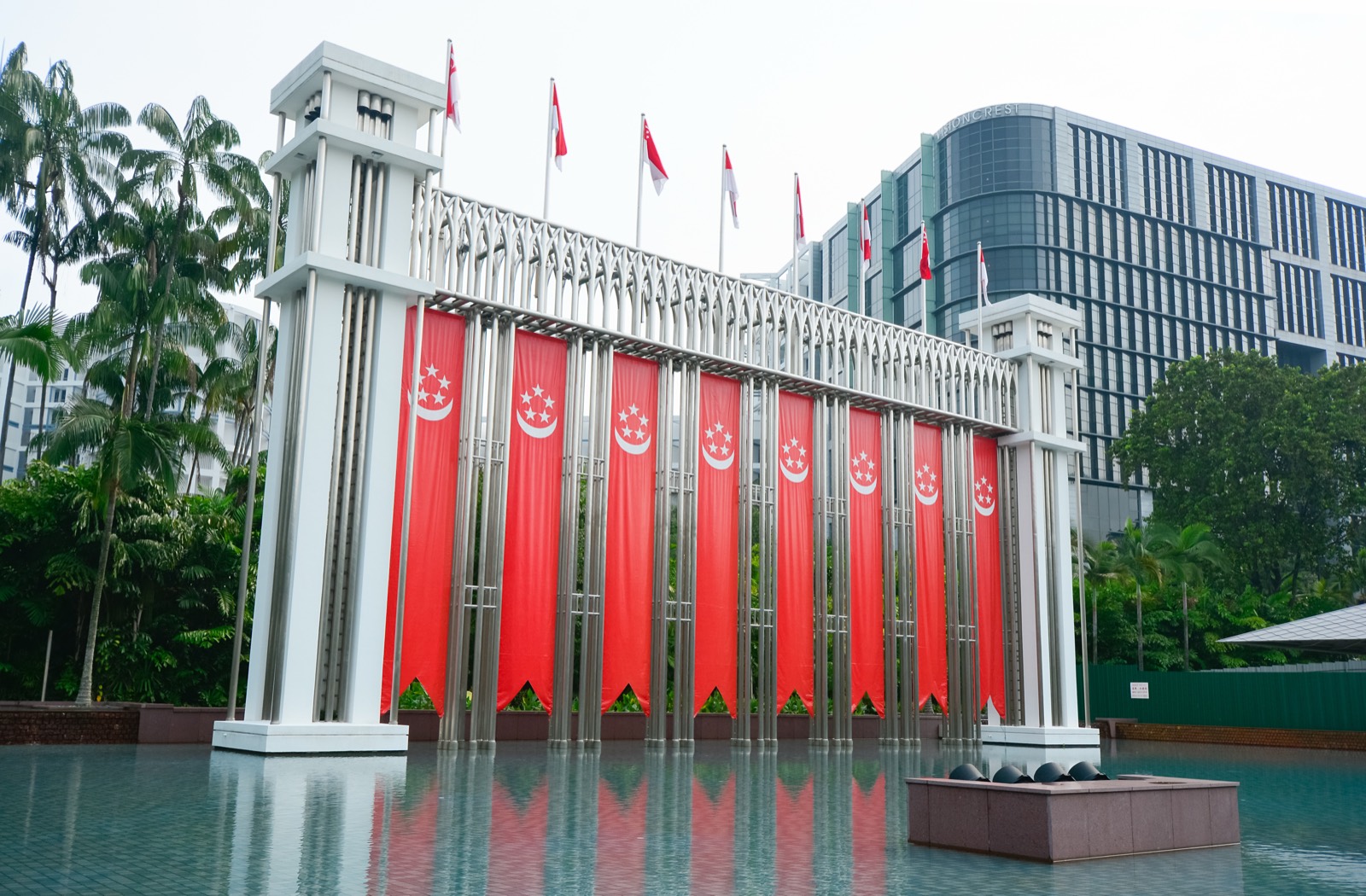Singapore flags on a monument in front of modern buildings